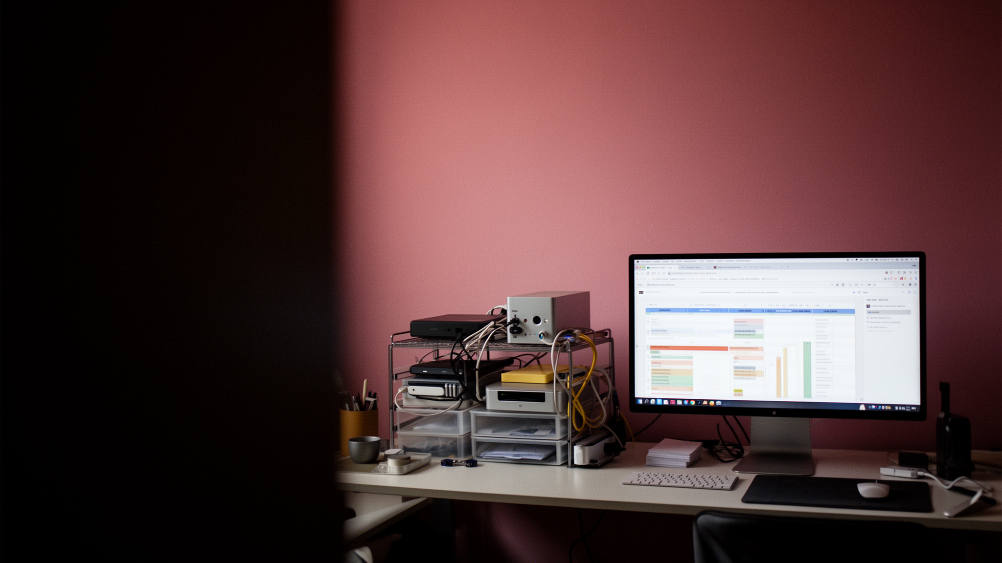 MacBook keyboard edge near paper ledger beneath window light on tidy desk